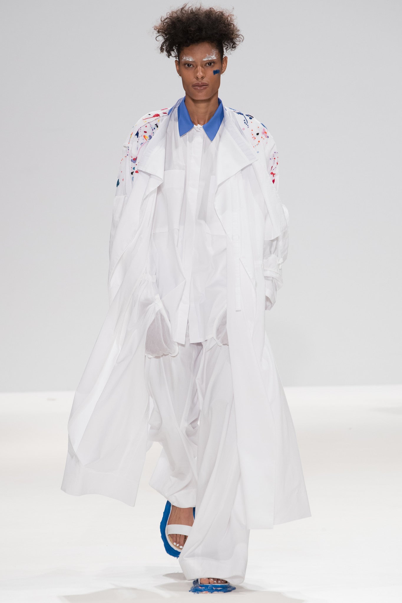 Catwalk image from CIMONE SS17 featuring model Vanessa David. Colourful embroidered paint splashes on crisp white cotton 'Helios' trench coat from emerging brand CIMONE. Embellishments and overall look at echoed by Oscar de la Renta one year later in SS18 - be ahead of the trends and support new brands!